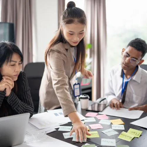 Équipe multiculturelle organisant des post-its sur une table pour piloter une stratégie RSE en entreprise
