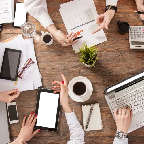 Vue du dessus d'une réunion de travail avec tablettes, documents et cafés pour préparer un audit RSE