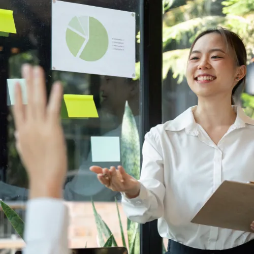 Consultante RSE souriante présentant un graphique en camembert vert à son équipe avec des post-its