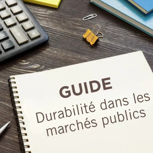 Guide pratique sur la durabilité dans les marchés publics posé sur un bureau avec calculatrice et fournitures