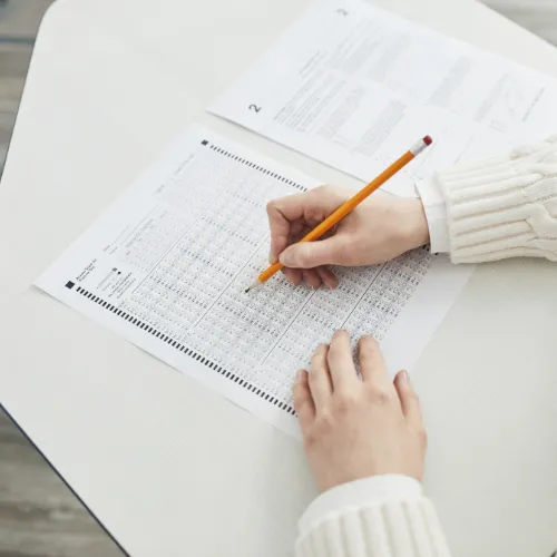 Mains remplissant un questionnaire RSE au crayon représentant la réponse à une évaluation de fournisseur