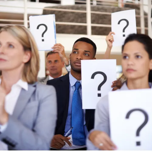 Professionnels en costume tenant des pancartes avec des points d'interrogation symbolisant les questions sur la CSRD pour les entreprises suisses