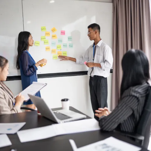 Équipe en réunion brainstorming avec post-its colorés sur tableau blanc pour préparer leur évaluation EcoVadis