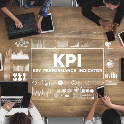 Vue aérienne d'une équipe en réunion autour d'une table avec une projection holographique "KPI – Key Performance Indicator" et des graphiques de performance RSE