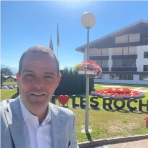 Portrait de François Morvan, directeur du Hilton Geneva Hotel & Conference Centre, devant un bâtiment fleuri
