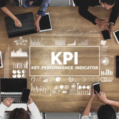 Luftaufnahme eines Teams, das sich um einen Tisch versammelt hat, mit einer holografischen Projektion „KPI – Key Performance Indicator“ und Grafiken zur CSR-Leistung